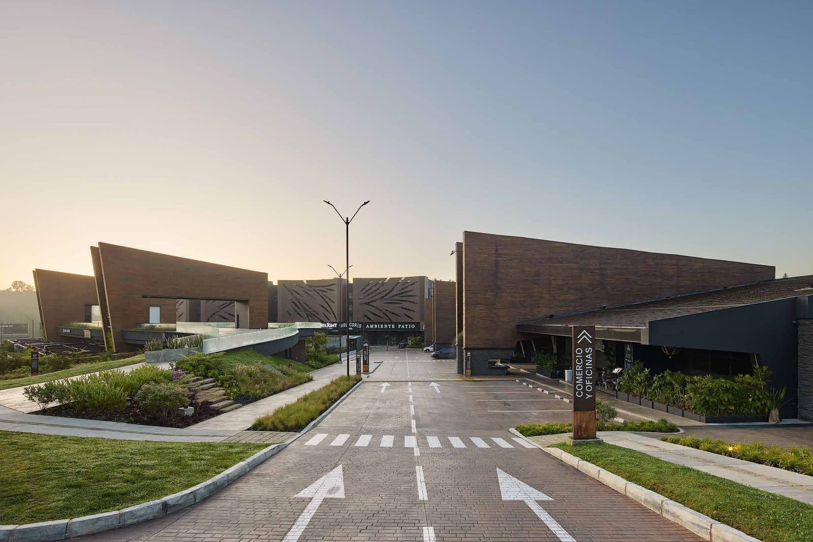 Mercado gastronómico de Vicaría Arquitectura al amanecer: volúmenes en acero corten y ladrillo sobre jardines